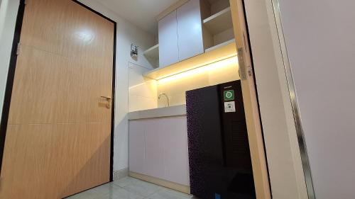 um corredor com uma porta que leva a uma cozinha com um lavatório em The Alton Apartemen Type Studio em Jatingaleh