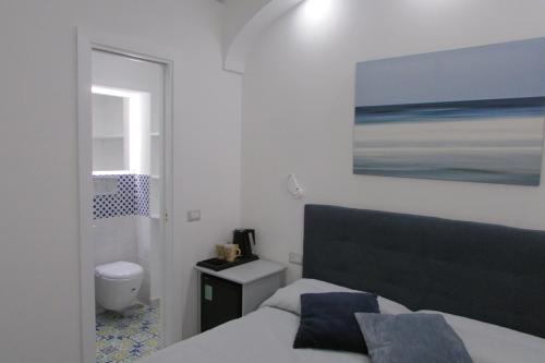 1 dormitorio con 1 cama y una pintura en la pared en Domus Claudia, en Atrani