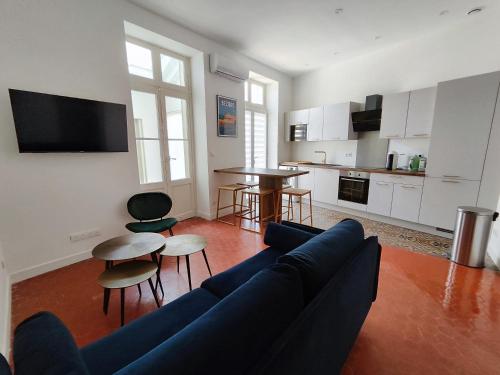 un salon avec un canapé bleu et une cuisine dans l'établissement Bright and modern 3-bedroom apartment, 90m2 with Air condition, in Beziers, à Béziers