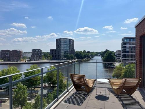 two chairs sitting on a balcony overlooking a river at Penthouse-Wohnung mit Flussblick in Oldenburg
