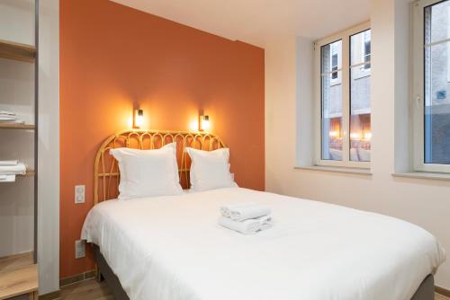 een slaapkamer met een groot bed met een oranje muur bij L'Annexe Metz Cathédrale in Metz