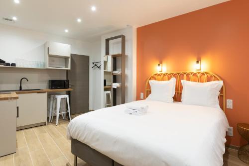 une chambre avec un grand lit blanc et une cuisine dans l'établissement L'Annexe Metz Cathédrale, à Metz