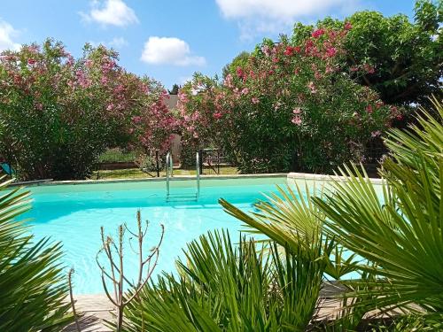 - une piscine entourée d'arbres et de fleurs roses dans l'établissement Maison de 2 chambres avec piscine privee jardin clos et wifi a Maillane, à Maillane