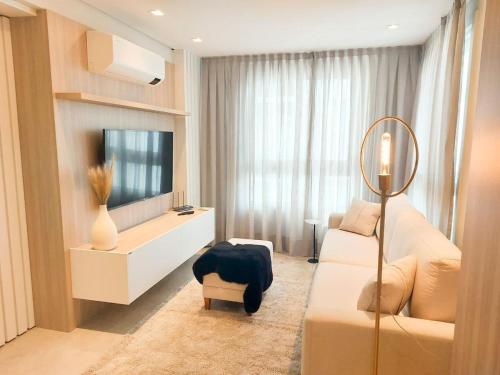 uma sala de estar com televisão e um sofá branco em VILLA DI TONDO HOUSE - APARTAMENTO ESPETACULAR em Bento Gonçalves