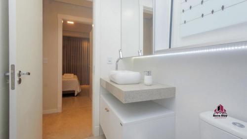 a white bathroom with a sink and a mirror at VILLA DI TONDO HOUSE - APARTAMENTO ESPETACULAR in Bento Gonçalves
