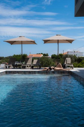 a woman laying on the edge of a swimming pool with umbrellas at Ria Formosa Guest House in Faro