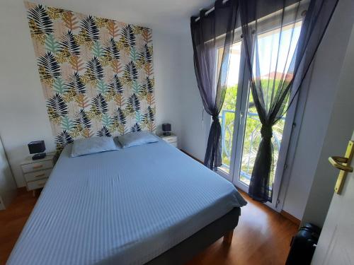 een slaapkamer met een bed en een groot raam bij Coeur Marina climatisé terrasse parking in Fréjus