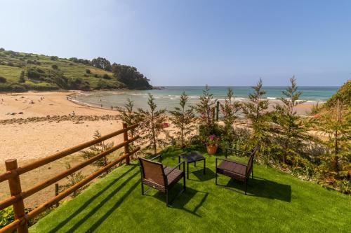 einen Balkon mit 2 Stühlen, einem Tisch und einem Strand in der Unterkunft Hotel SanMar in Cóbreces