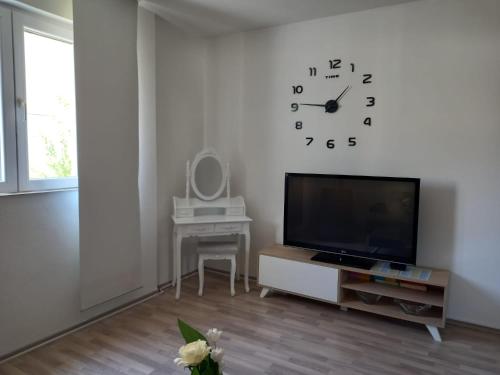 a living room with a tv and a clock on the wall at Apartman Zara in Zadar