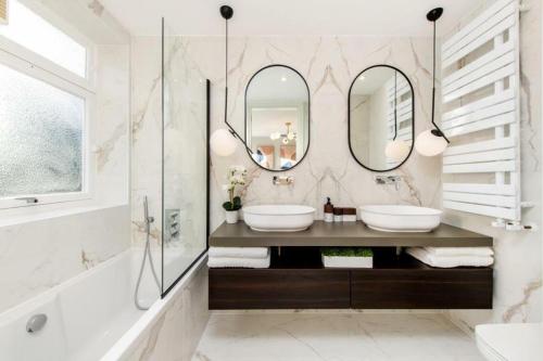 a bathroom with two sinks and two mirrors at Ultra Luxury Central London 3Bed Apartment in London