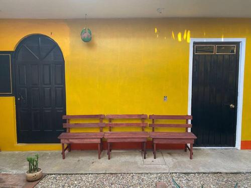 two benches sitting in front of a yellow wall at Encantadora casa tradicional con terraza in Oaxaca City