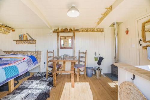 1 dormitorio con 1 cama, mesa y sillas en Littlestock Shepherds Hut, en Shipton under Wychwood
