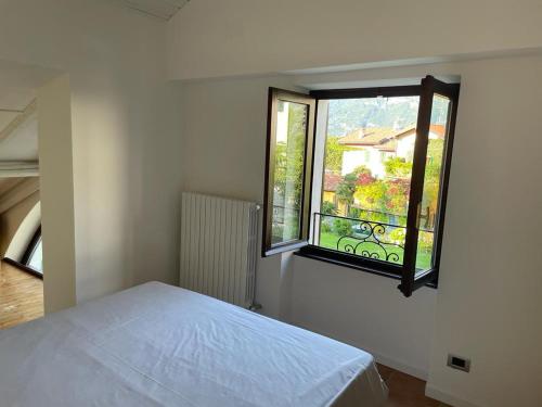 a bedroom with a white bed and a window at Casetta Mary in Bellagio