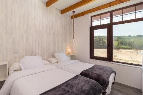 two beds in a room with a view of a beach at Hotel SanMar in Cóbreces