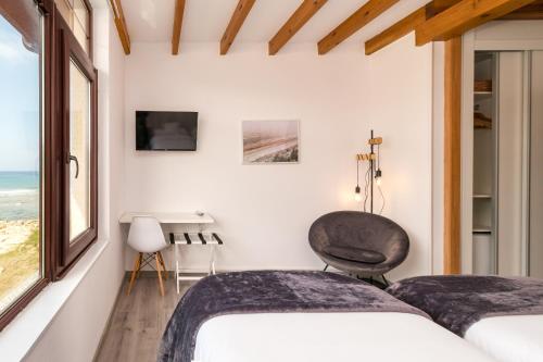 a bedroom with two beds and a chair at Hotel SanMar in Cóbreces
