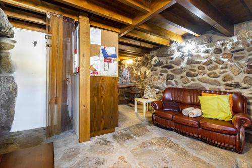 a leather couch in a room with a stone wall at Isatour Casa na Serra in Adsamo