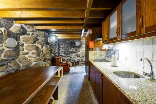 cocina con fregadero y pared de piedra en Isatour Casa na Serra, en Adsamo