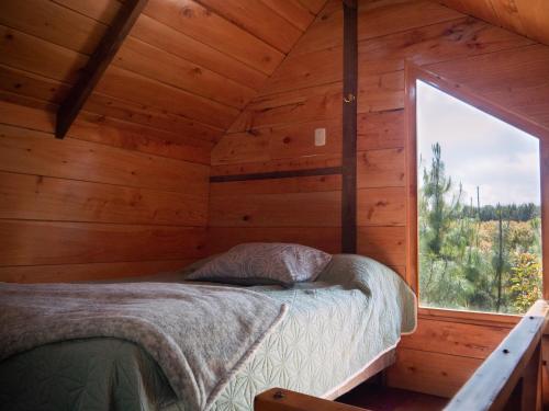 a bedroom in a log cabin with a bed and a window at Charming cabin surrounded by nature in El Escudero