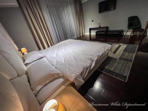 a bedroom with a white bed and a piano at Pensiunea White Department in Vlădeşti
