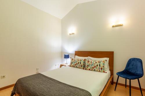 um quarto com uma cama e uma cadeira azul em Casa Nogueira - Minho's Guest em Pousadouros