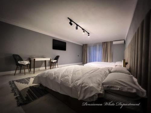 a bedroom with a bed and a table with chairs at Pensiunea White Department in Vlădeşti