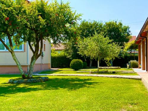 a green yard with trees and a house at Apartment Helena Airport in Podgorica