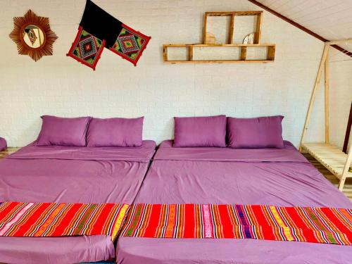 a bedroom with two beds with purple sheets and flags at Pết house Mộc Châu in Mộc Châu