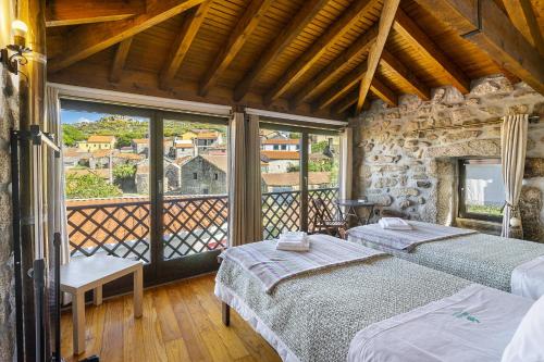 1 dormitorio con 2 camas y ventana grande en Isatour Casa na Serra, en Adsamo