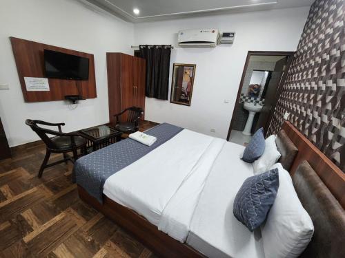 a bedroom with a bed and a desk and a television at Hotel Aerotech Suite in New Delhi