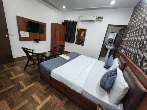 a bedroom with a bed and a desk and a television at Hotel Aerotech Suite in New Delhi