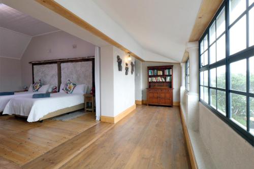 a bedroom with a bed and large windows at THE PLACE Muizenberg in Muizenberg