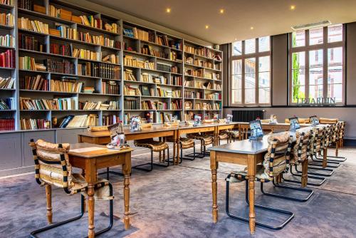 a library with tables and chairs and bookshelves at Les Maisons de Lea, a member of Radisson Individuals in Honfleur