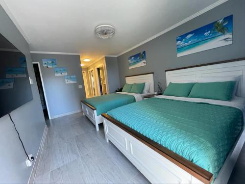 two beds in a bedroom with blue and green sheets at Waikiki Condo 2 Bedrooms 2 Bathrooms with 1 free parking space in Honolulu
