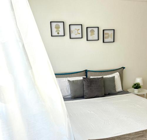 a bedroom with a white bed with four pictures on the wall at Modern Studio near Lugano's Lake & City Center in Lugano