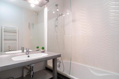 a white bathroom with a sink and a shower at Les Thermes 508 - Appt avec piscine partagée in Concarneau