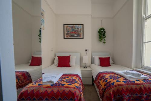 a room with two beds with red pillows at Montpellier Regency apartment balcony & parking in Cheltenham