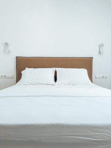 a white bed with a brown headboard and white pillows at Aphrodite's Villa in Ambelas