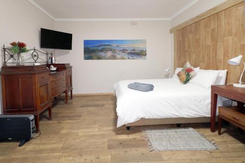 a bedroom with a bed and a dresser and a television at THE PLACE Muizenberg in Muizenberg