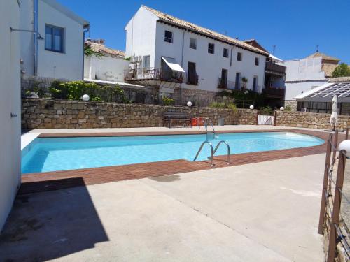 a swimming pool with a wooden deck next to a building at Luz del Renacimiento Ubeda in Úbeda