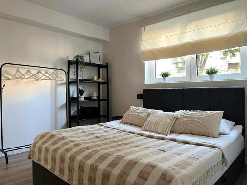a bedroom with a bed with a striped blanket and two windows at Apartament Niko Nad Zatoką Pucką in Puck