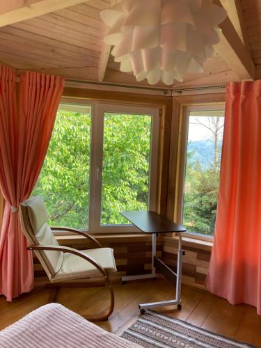 a room with a table and a chair and a window at Хата Різьбяра - Закуток in Beloberëzka