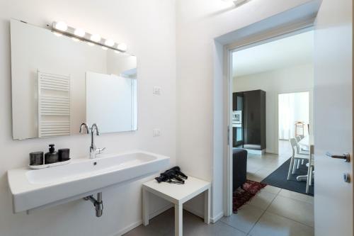 a white bathroom with a sink and a mirror at Carly's Rooms in Nago-Torbole