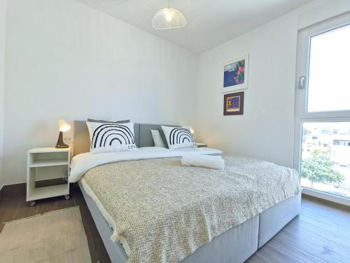 a white bedroom with a large bed and a window at Apartment Nonna in Split
