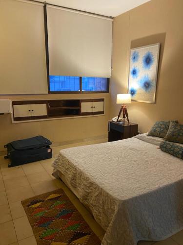 a bedroom with a bed and a window and a suitcase at Apartamento Valledupar, exclusivo, cómodo y residencial in Valledupar