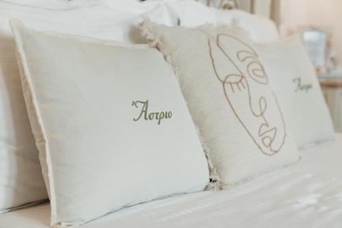 a white bed with white pillows on it at Astrio Suites in Livadion