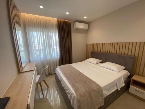 1 dormitorio con cama, escritorio y ventana en Olivia's Apartments en Velipojë