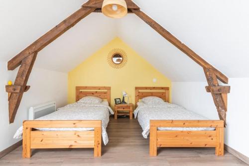 Cette chambre mansardée comprend 2 lits et des poutres apparentes. dans l'établissement La grange de Merlin, à Concoret