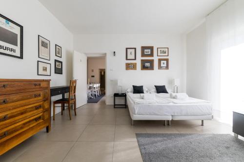 a white bedroom with a bed and a desk at Carly's Rooms in Nago-Torbole