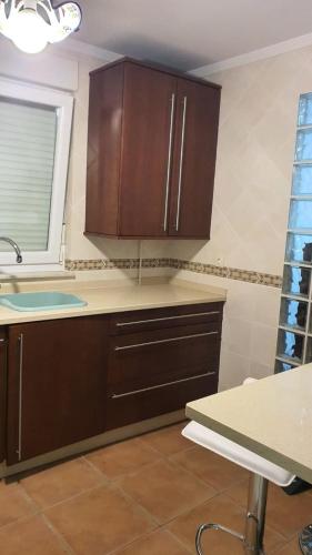 a kitchen with wooden cabinets and a sink at ALOJAMIENTO TEATRO in Ribadeo
