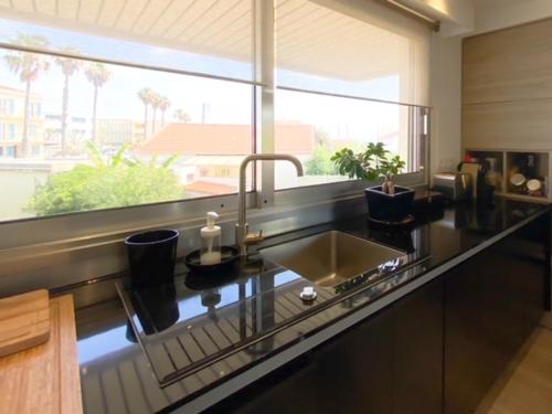 une cuisine avec un évier et une grande fenêtre dans l'établissement Charmant appartement proche des plages, à Antibes